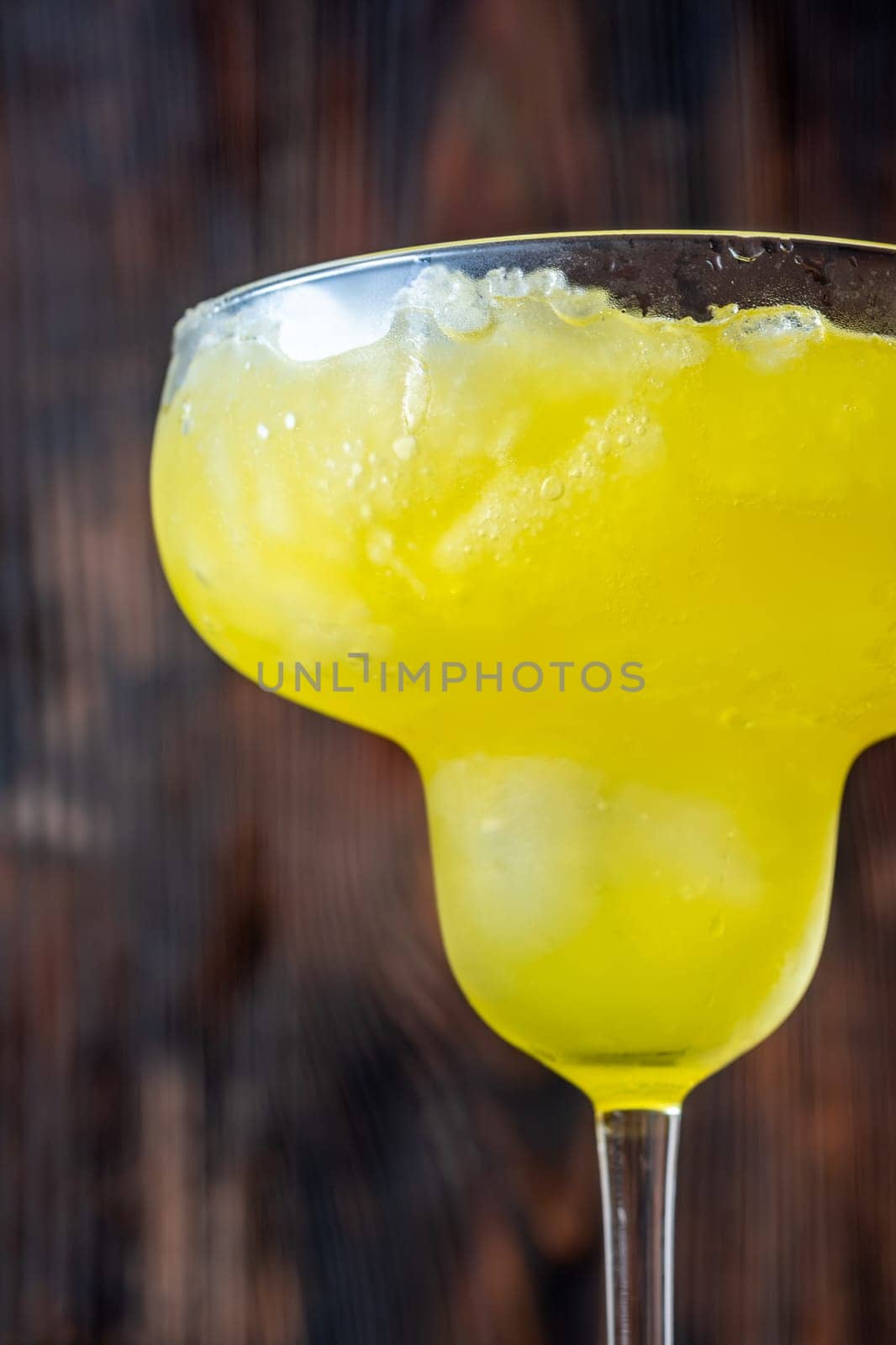 Frozen banana margarita cocktail on rustic wooden table