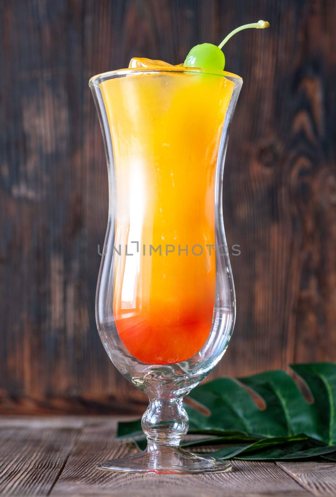 Banana Rum Punch cocktail garnished with green maraschino cherry