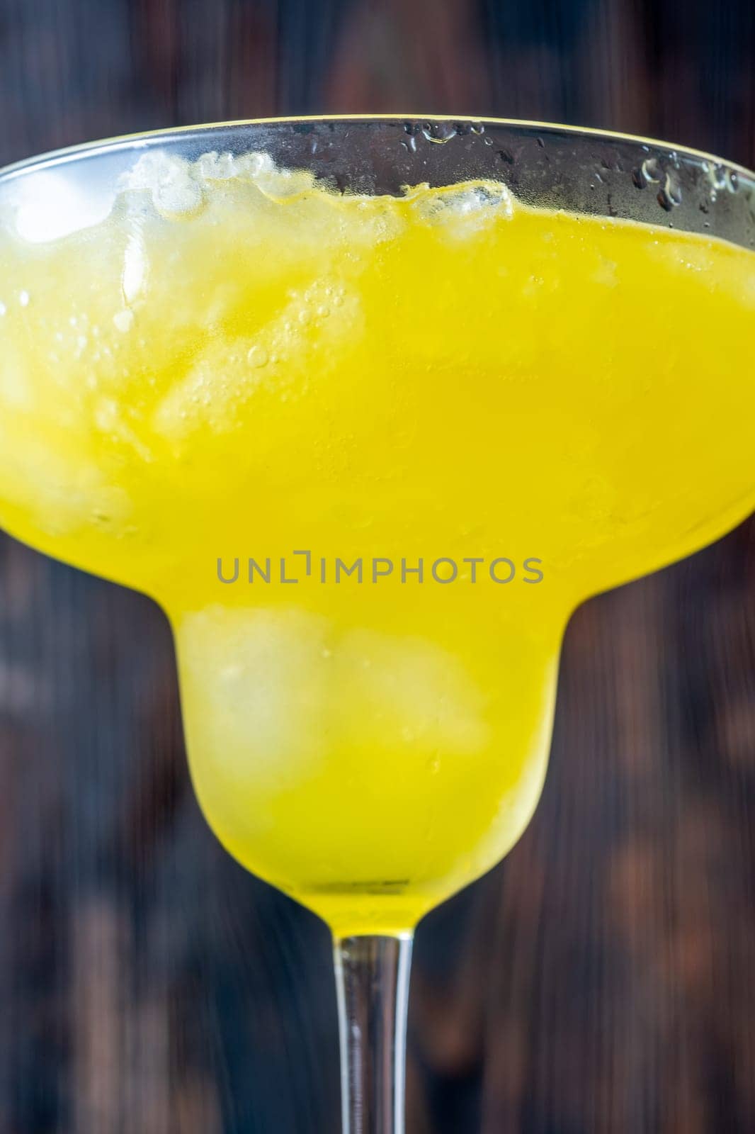 Frozen banana margarita cocktail on rustic wooden table