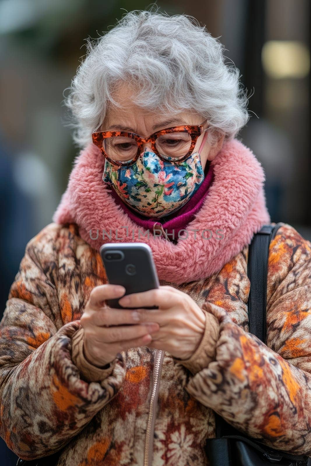 Senior woman wearing a face mask and looking at her smartphone while walking in the city