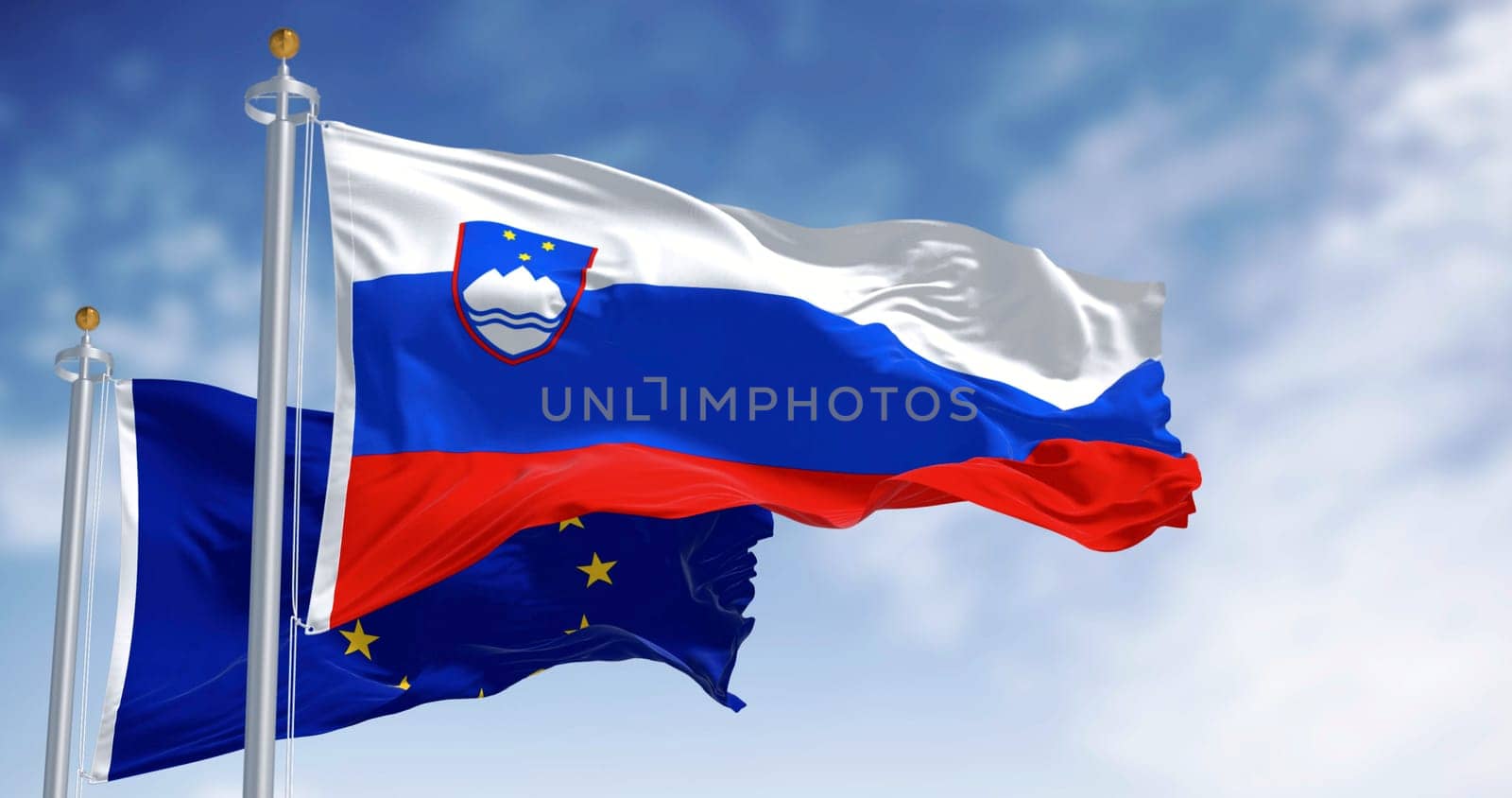 Flags of Slovenia and the European Union fluttering together on a clear day. Slovenia has been a member of the eurozone since January 1, 2007. 3D illustration render. Fluttering fabric