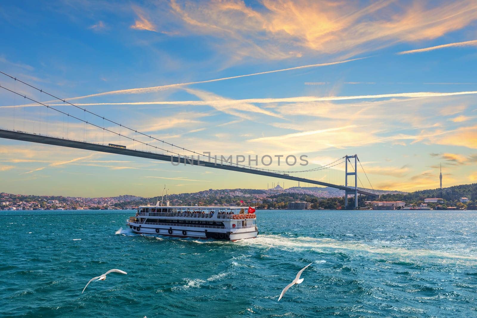 Cruise ship is sailing under the Bosphorus bridge, sunset view, Istanbul, Turkey.