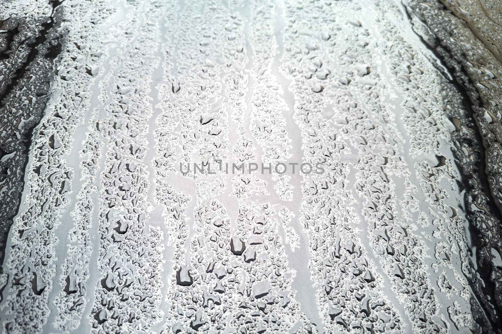 rain water drops on a bonnet of a black car during rainy day, full-frame closeup view