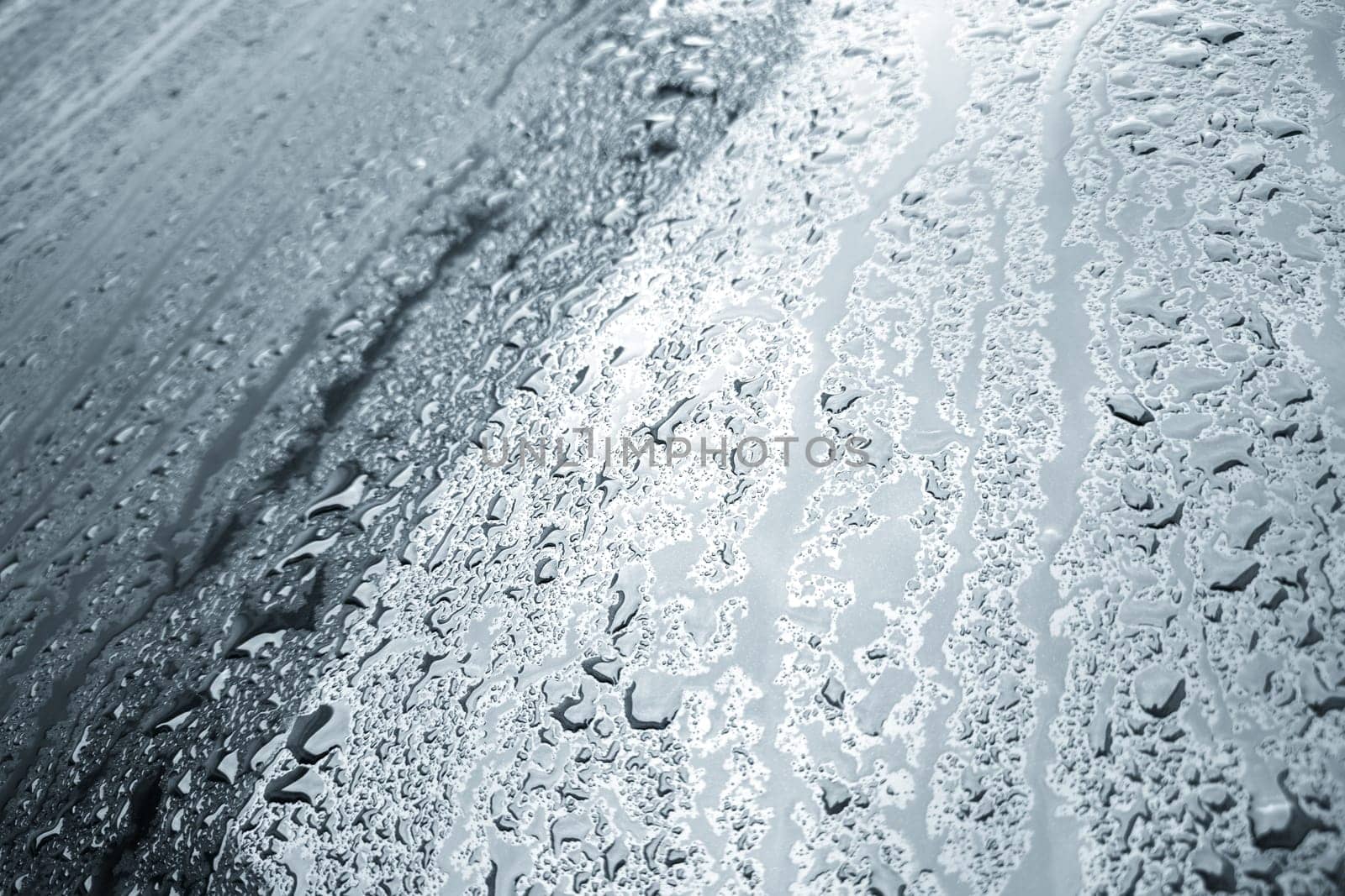 rain water drops on a bonnet of a black car during rainy day, full-frame closeup view