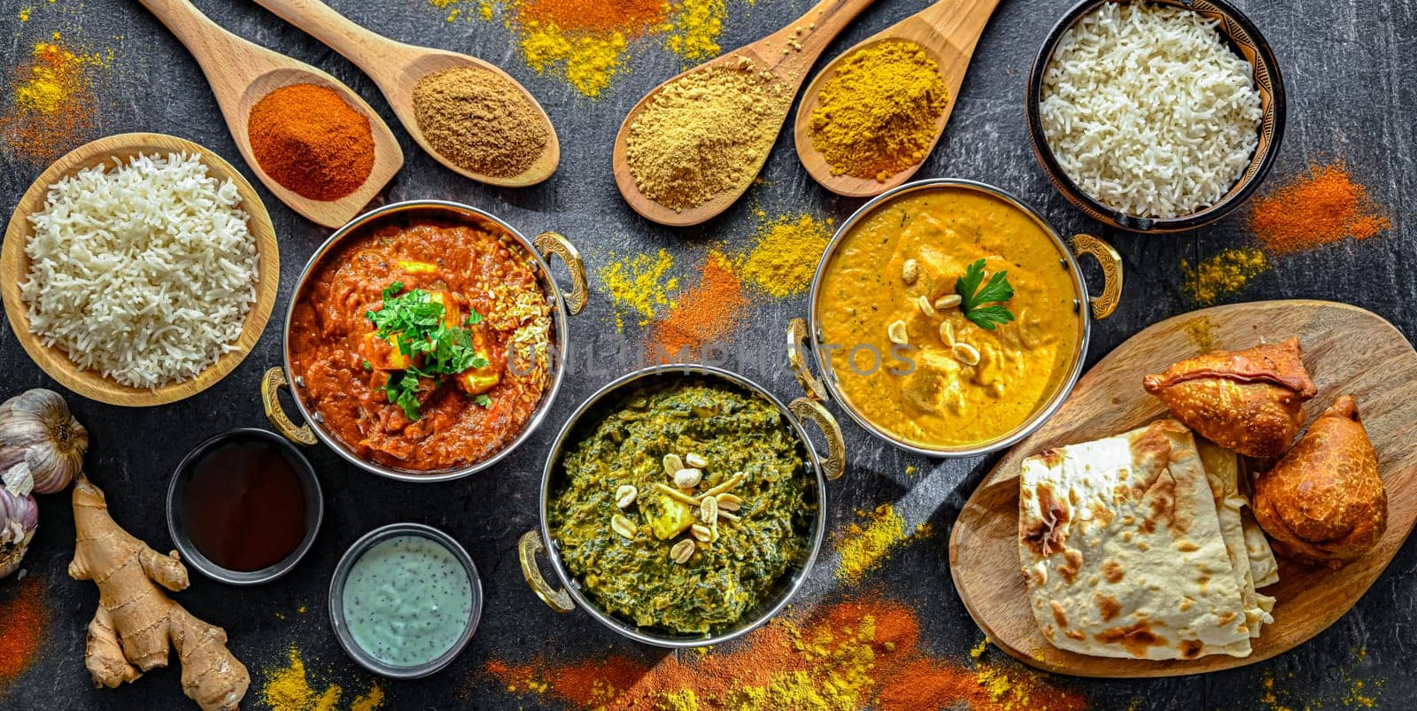 Composition with Indian dishes: madras paneer, palak paneer and shahi paneer with basmati rice served in original indian karahi pots