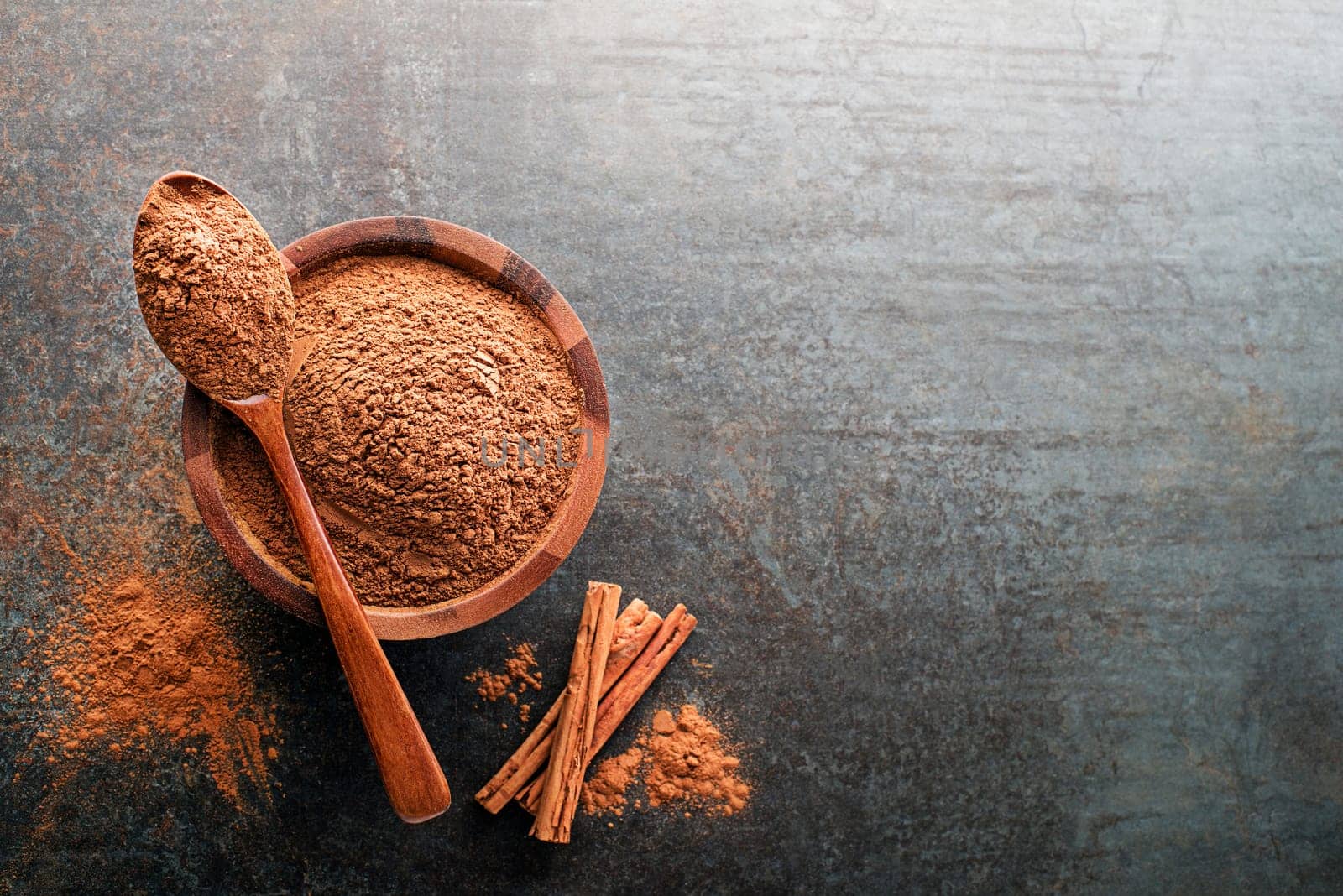 Aromatic cinnamon powder and sticks with spoon on grey background close up