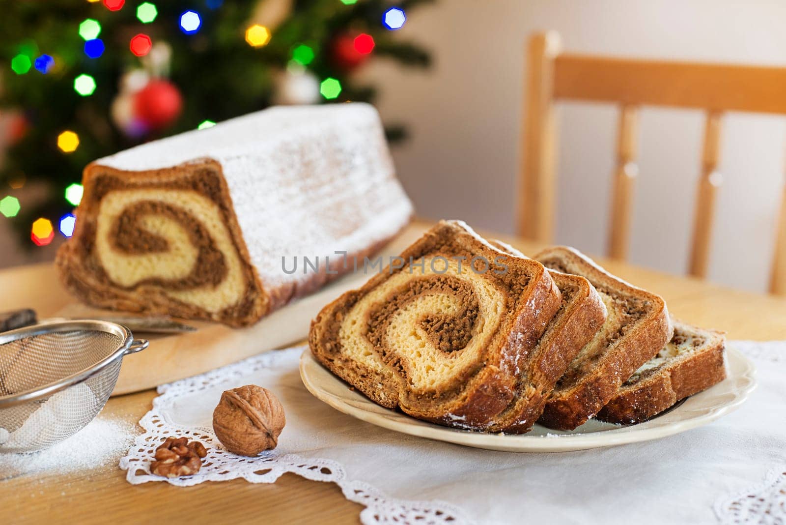 Christmas holidays celebration dessert. Potica, traditional Slovenian bread cake roll in front of christmas tree