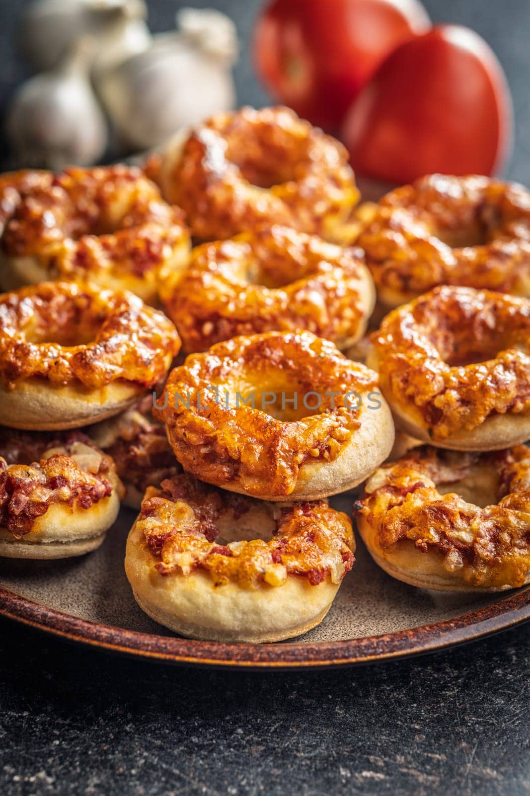 Mini pizza bagels on plate on a black table.