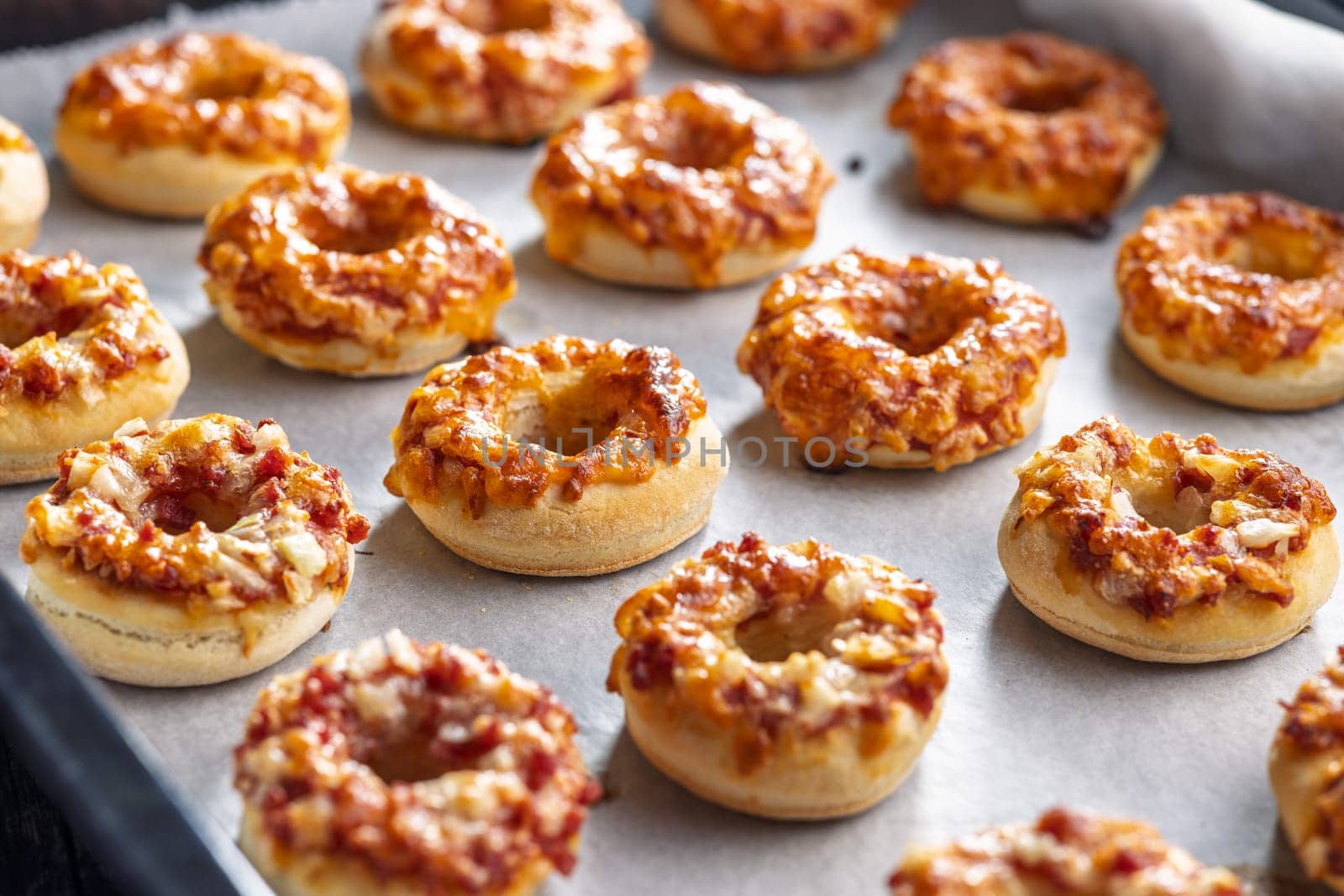 Mini pizza bagels on a baking paper.