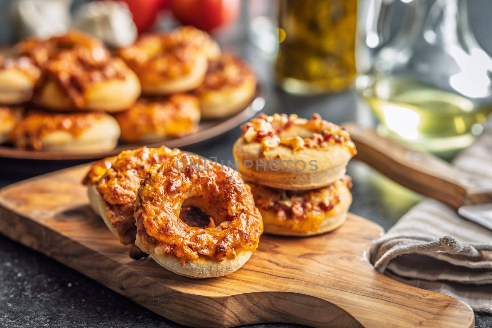 Mini pizza bagels on cutting board on a black table.