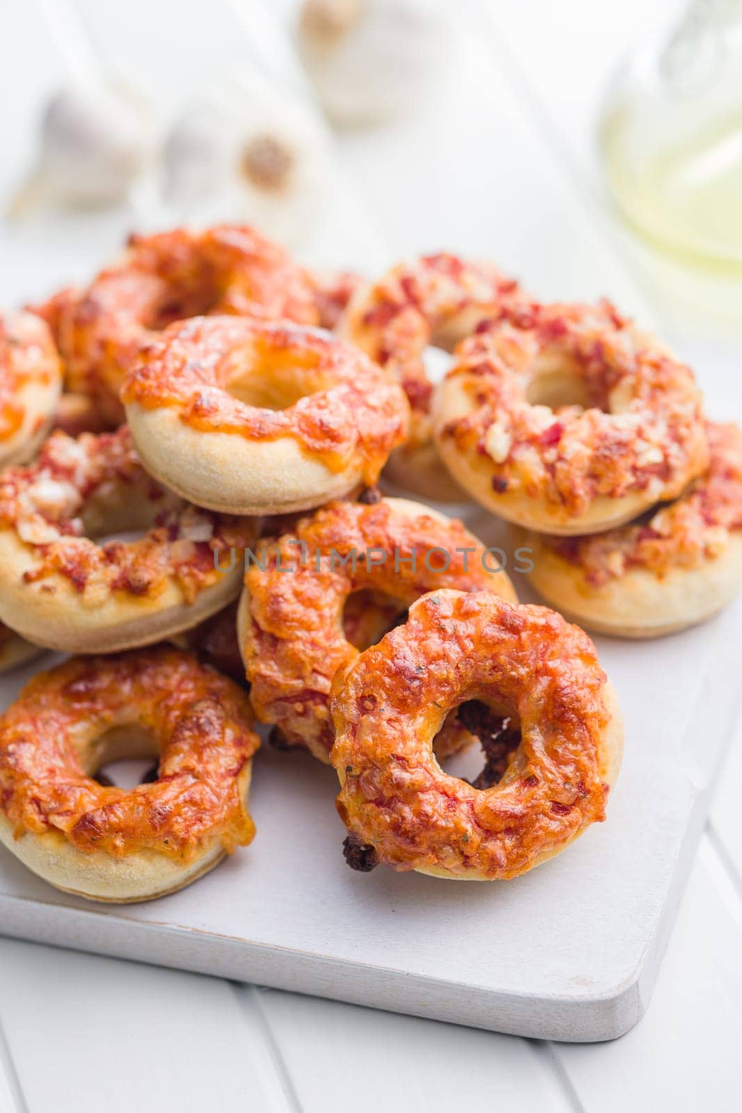 Mini pizza bagels on cutting board on a white table.