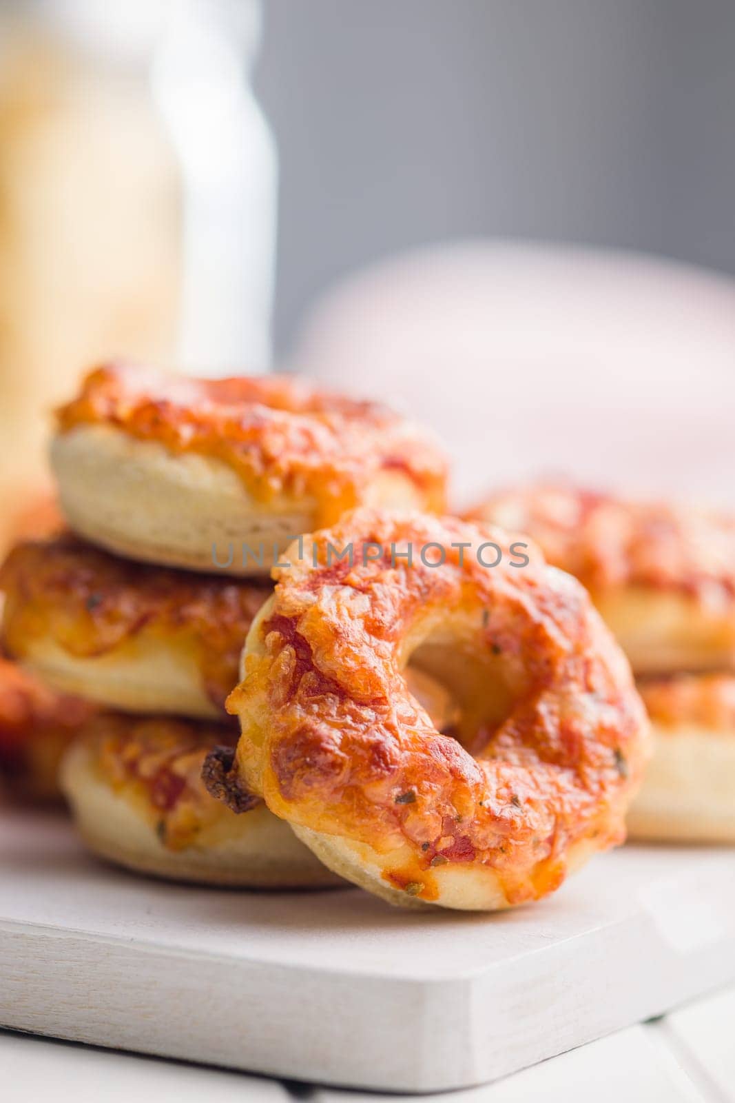 Mini pizza bagels on cutting board on a white table.