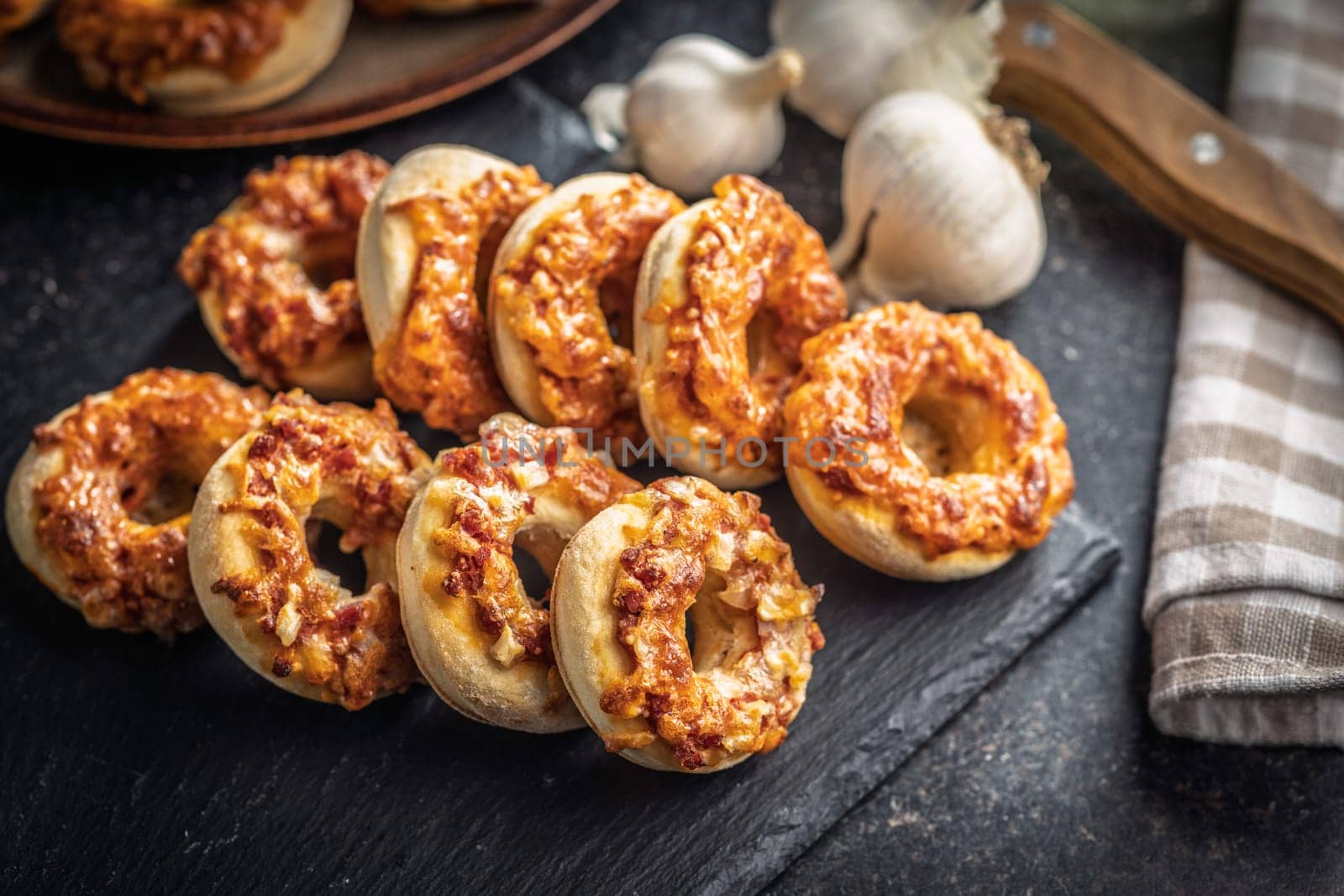 Mini pizza bagels on cutting board on a black table.