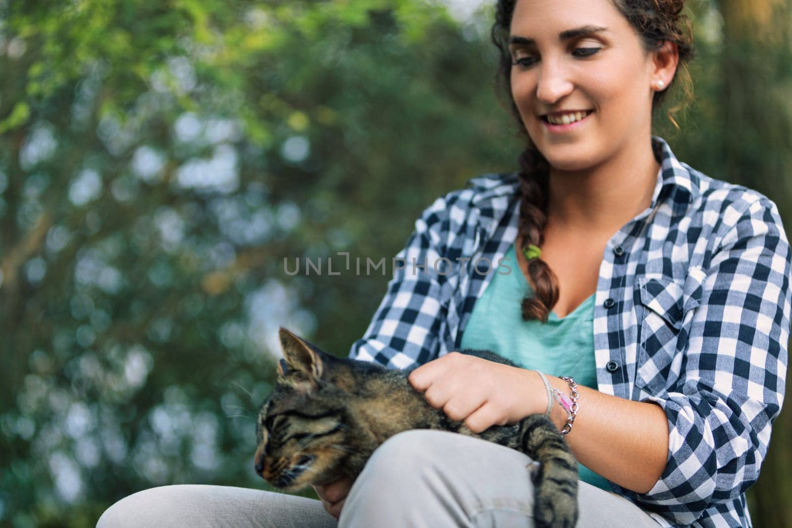 Young woman cuddles her tabby cat in a serene forest, surrounded by nature's embrace