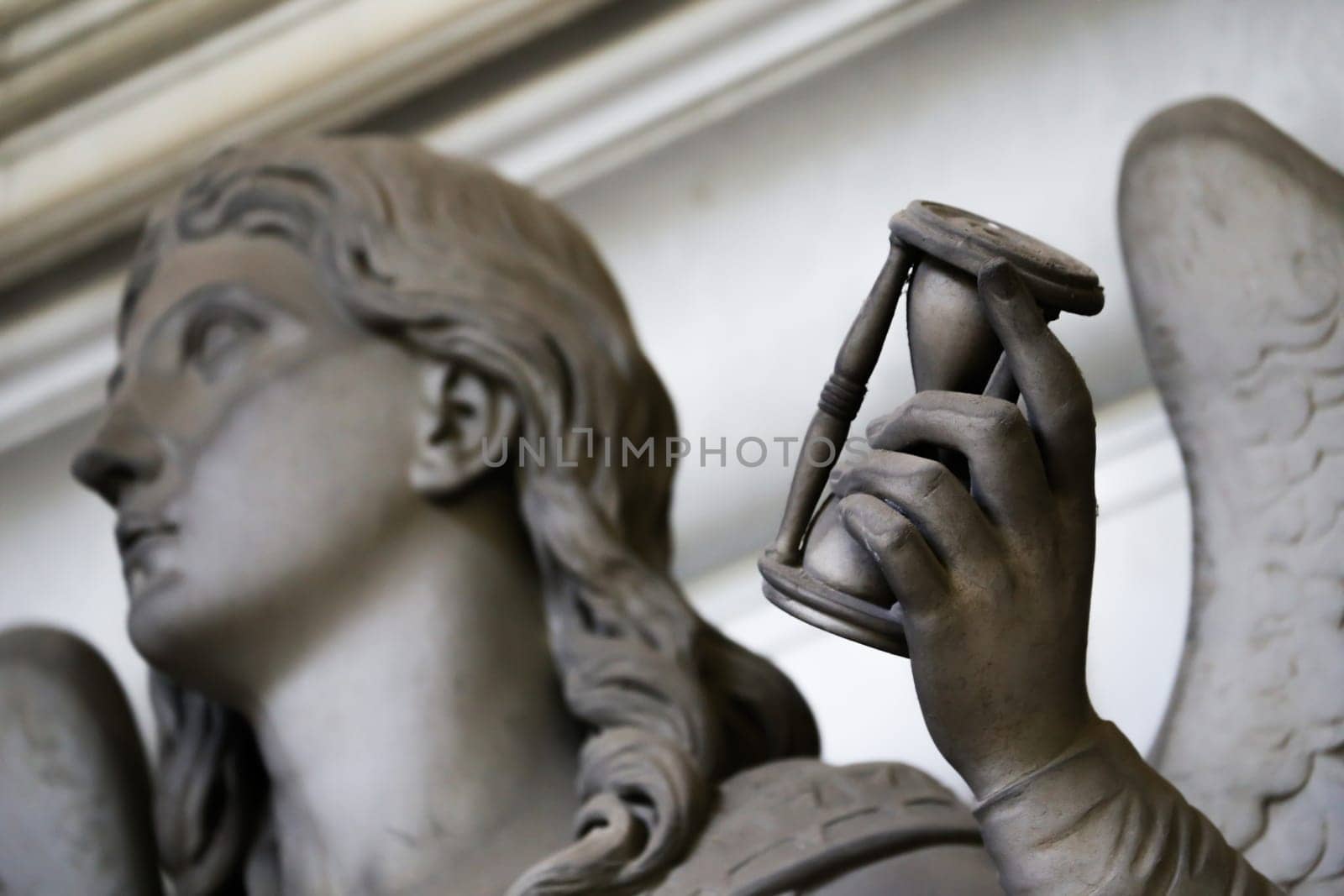 Antique statue holding a sandglass. Concept of time passing, countdown, retro hourglass