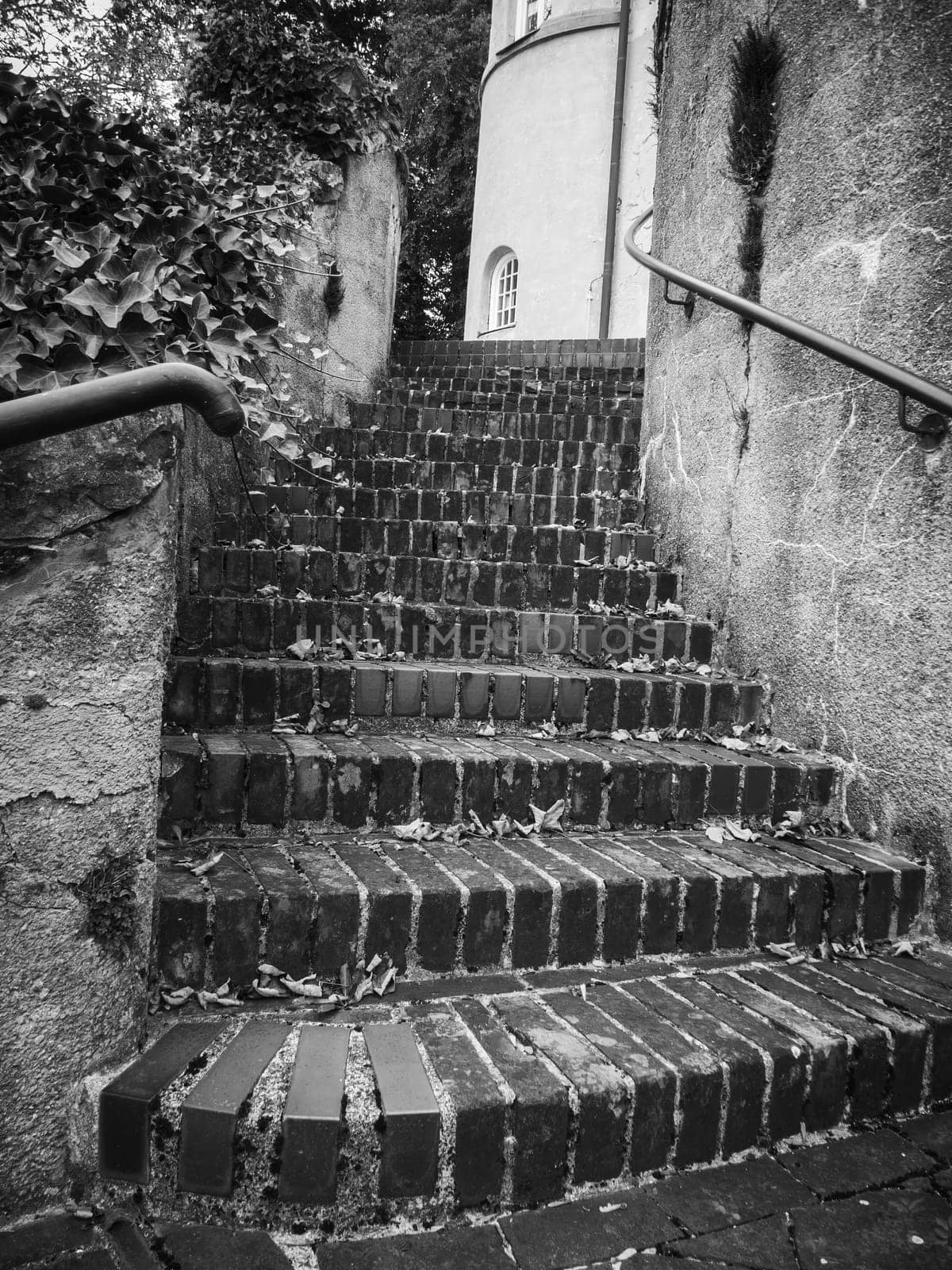Old brick staircase on a ruin wall with railing in black and white.