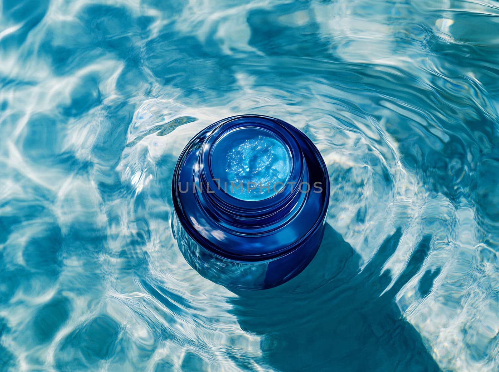 A rounded blue container rests atop calm water, reflecting the sunlight. The ripples create a shimmering effect around it.