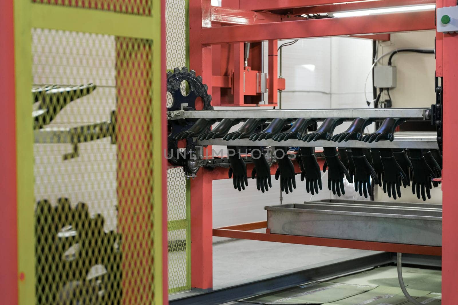 Close-up of a manufacturing machine producing gloves in an industrial factory, showcasing automation and production processes.