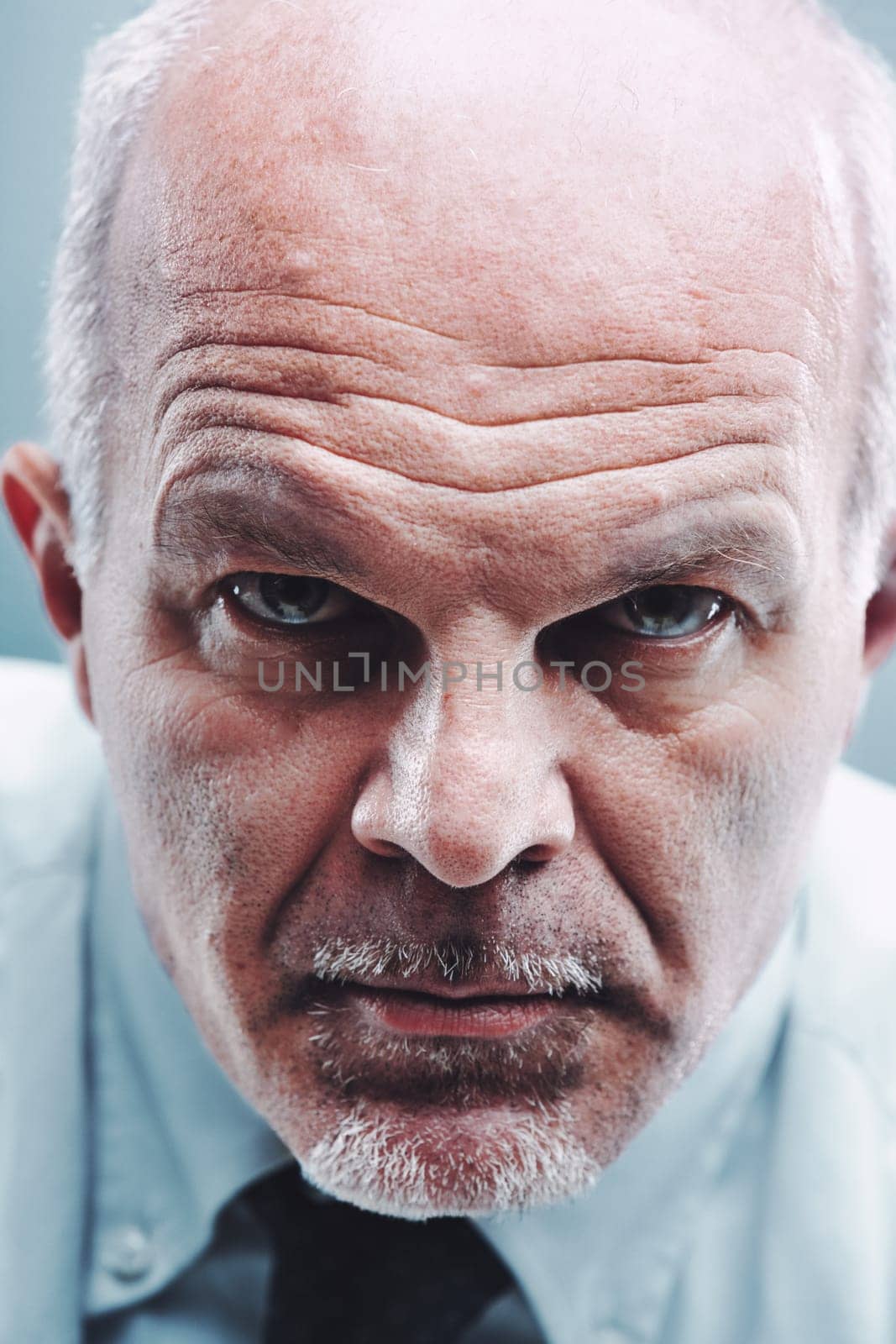 Close-up portrait of a serious mature businessman with a stern expression staring intensely at the camera, conveying authority, focus, and determination