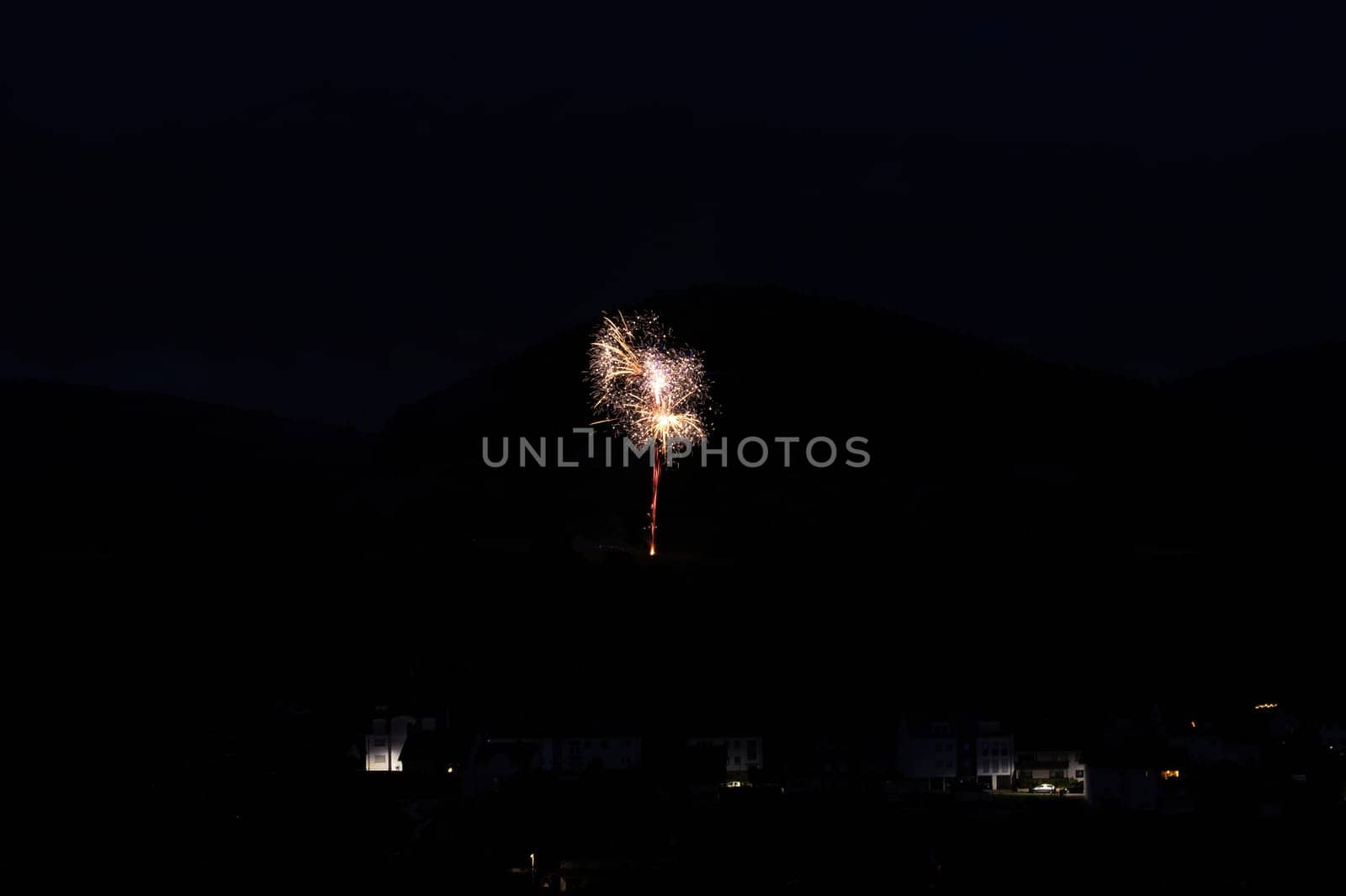A firework rocket in the sky on a mountain at night, a few illuminated houses in the foreground,A firework rocket in the sky on a mountain at night, a few illuminated houses in the foreground
