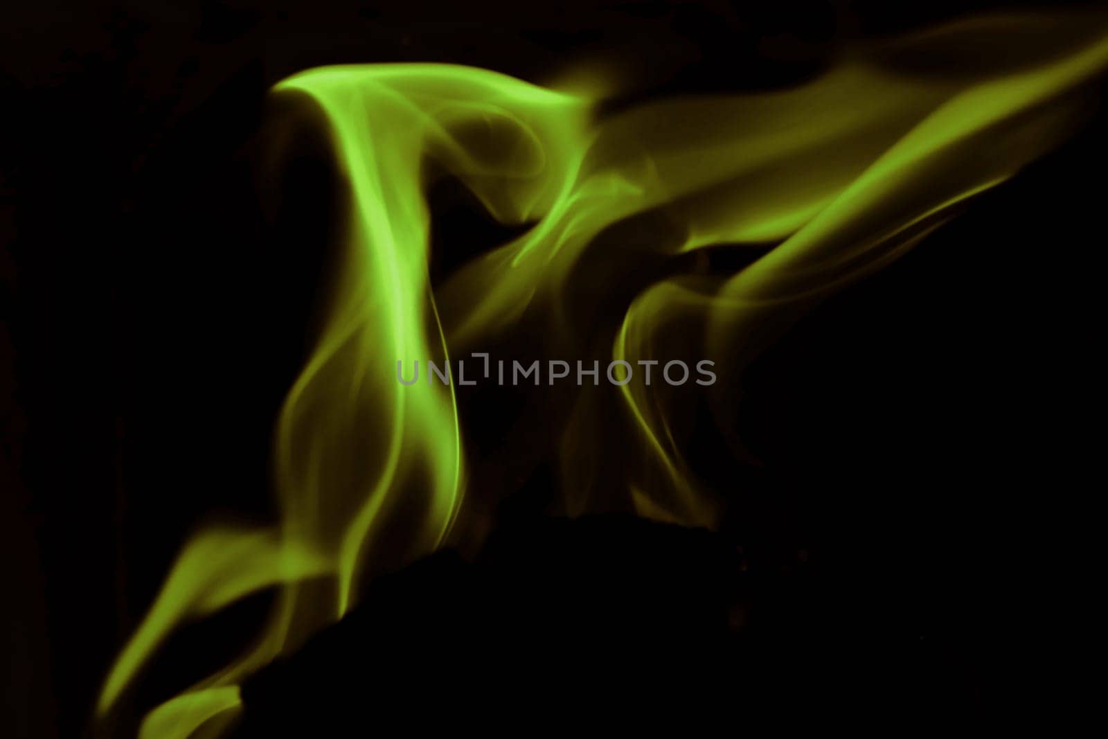 Flames from a fire in green and gold against a black background
