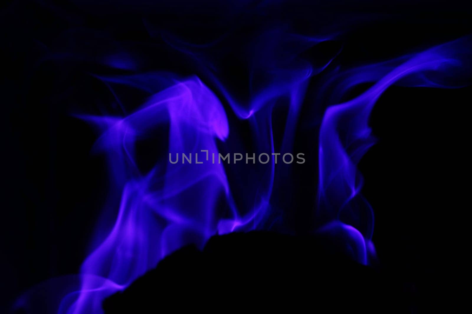 Flames from a fire in blue against a black background