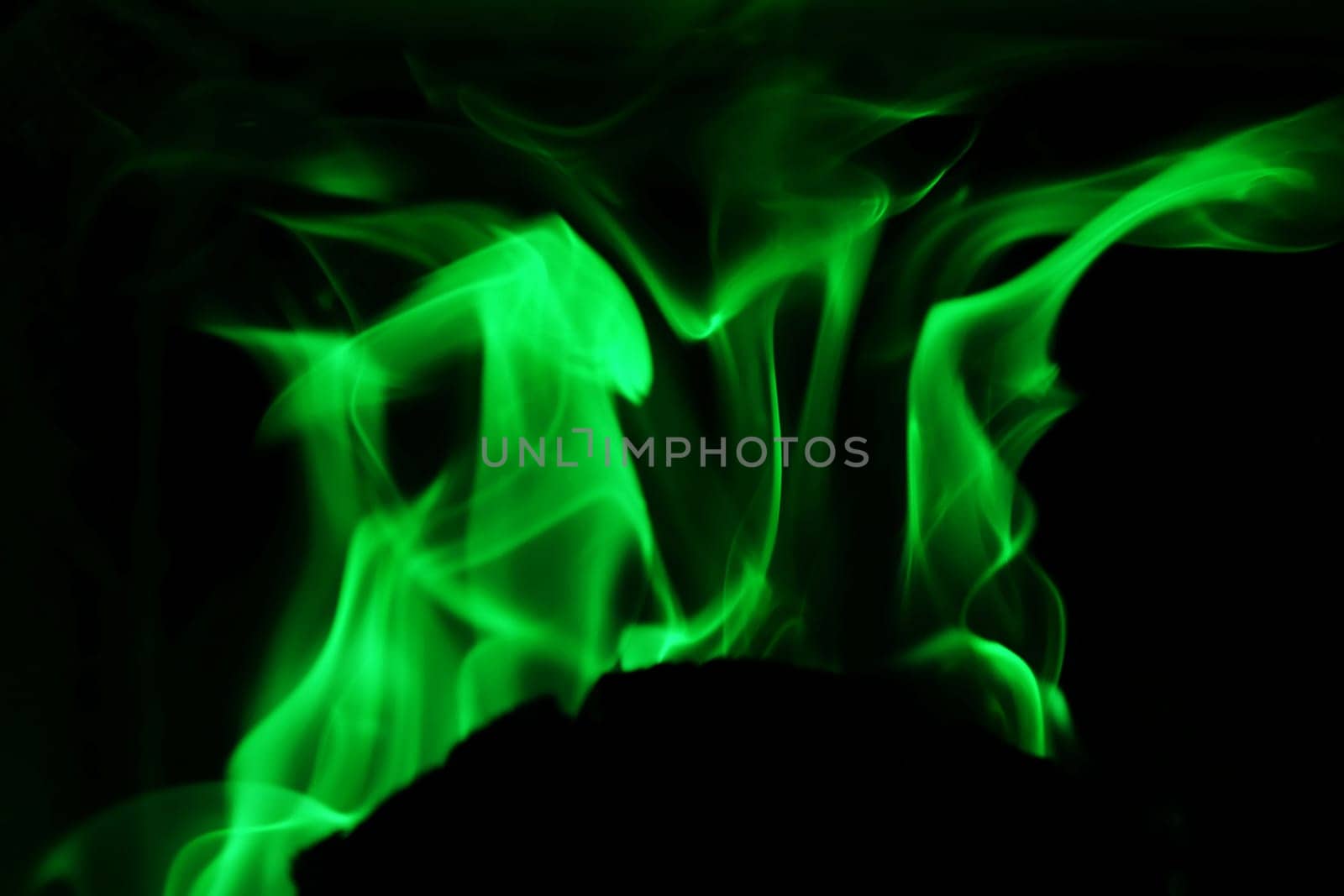 Flames from a fire in green against a black background