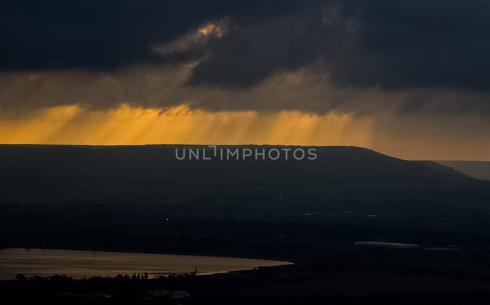 Dawn in the mountains of Crimea. A light haze of mist over the mountains and rays of the sun through the clouds.