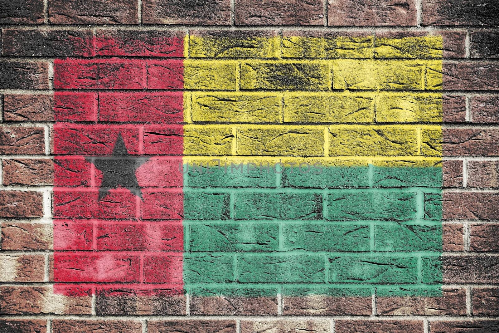 A Guinea-Bissau flag on brick wall background red yellow green star black