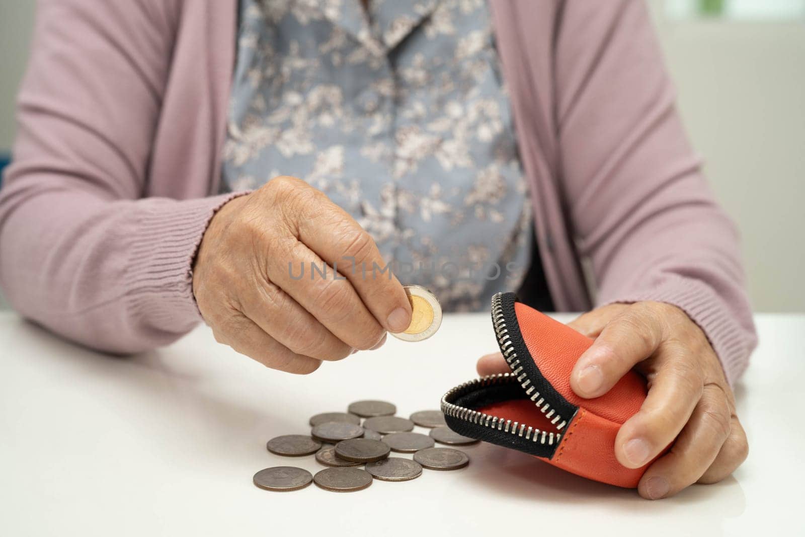 Asian senior or elderly old lady woman holding counting coin money in bag. Poverty, saving problem in retirement.