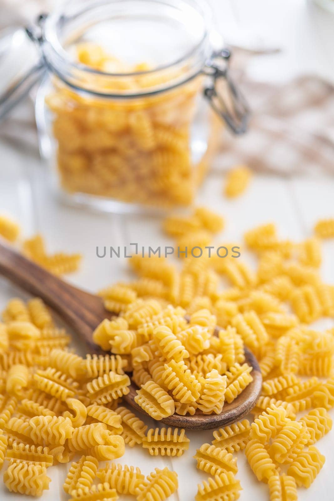 Uncooked italian pasta. Radiatori pasta in spoon on a white table.