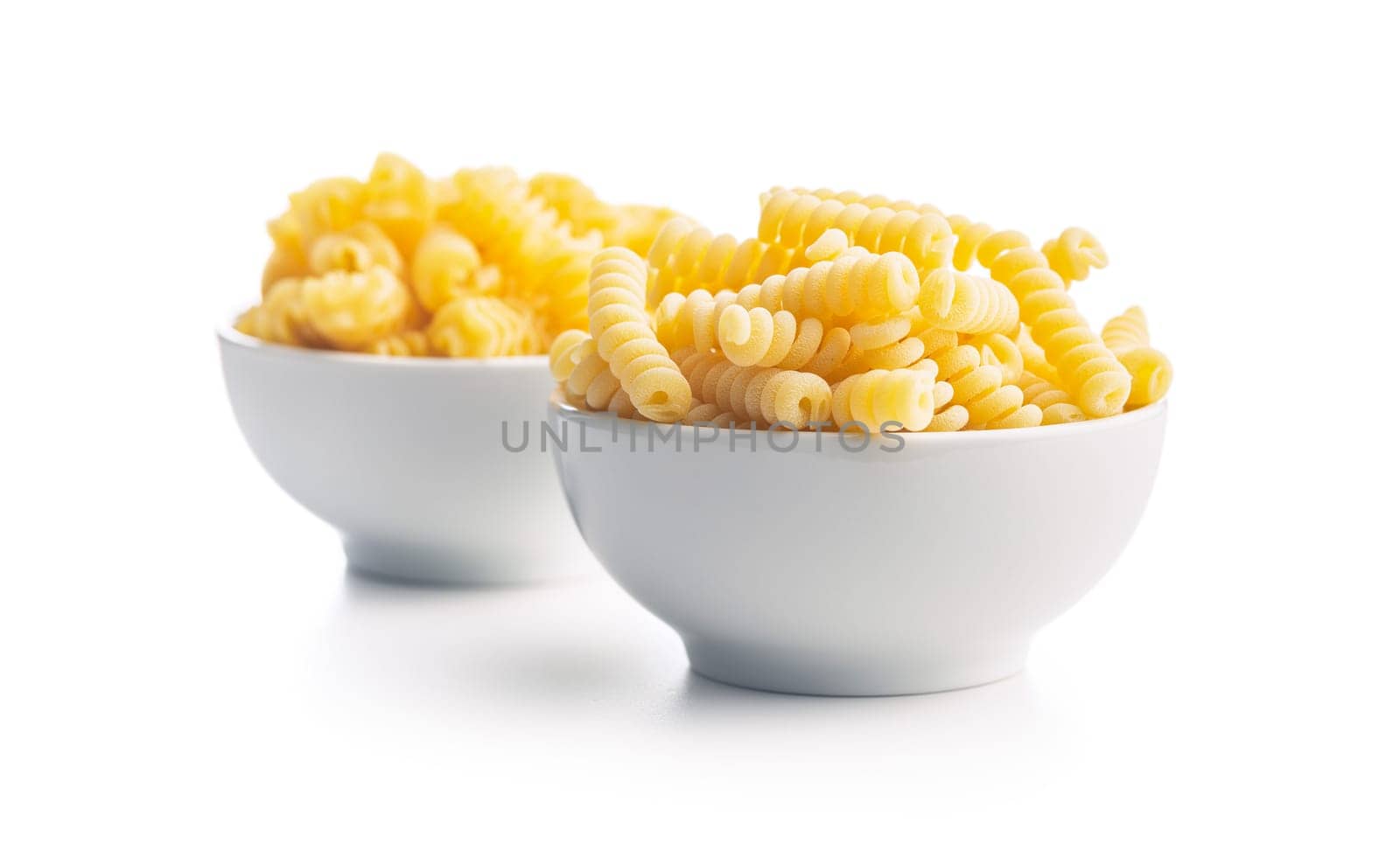 Uncooked italian pasta. Fusilli pasta in bowl isolated on a white background.
