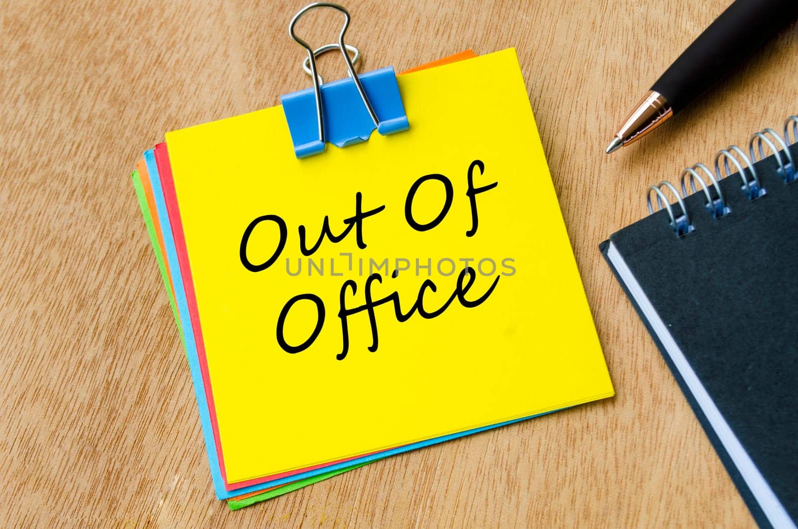 Top view of Out of Office text on yellow notepad. Holiday or vacation and away from work concept.