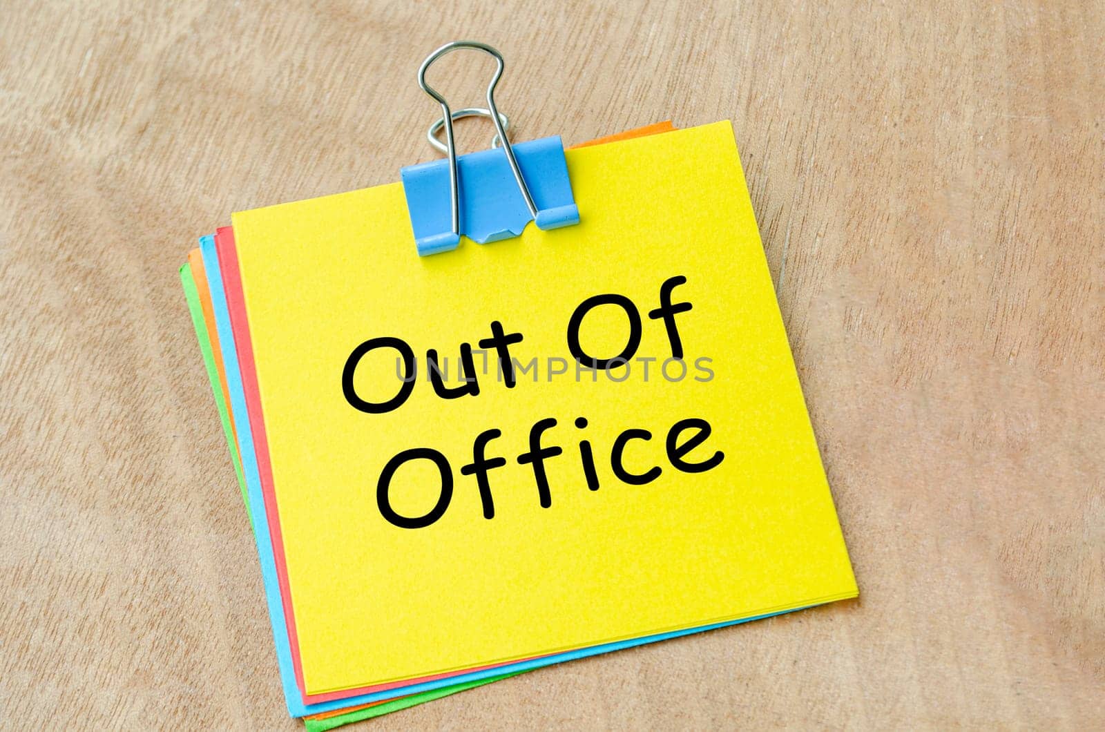 Top view of Out of Office text on yellow notepad. Holiday or away from work concept.