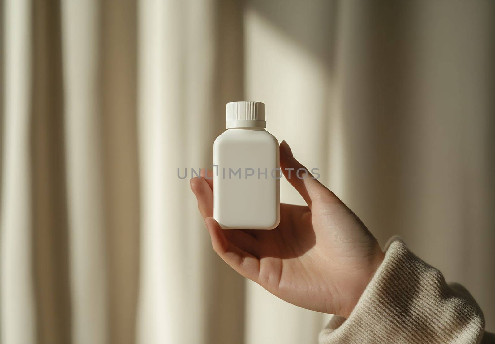 A hand holds a plain white bottle against soft, flowing curtains, creating a tranquil and minimalistic atmosphere.