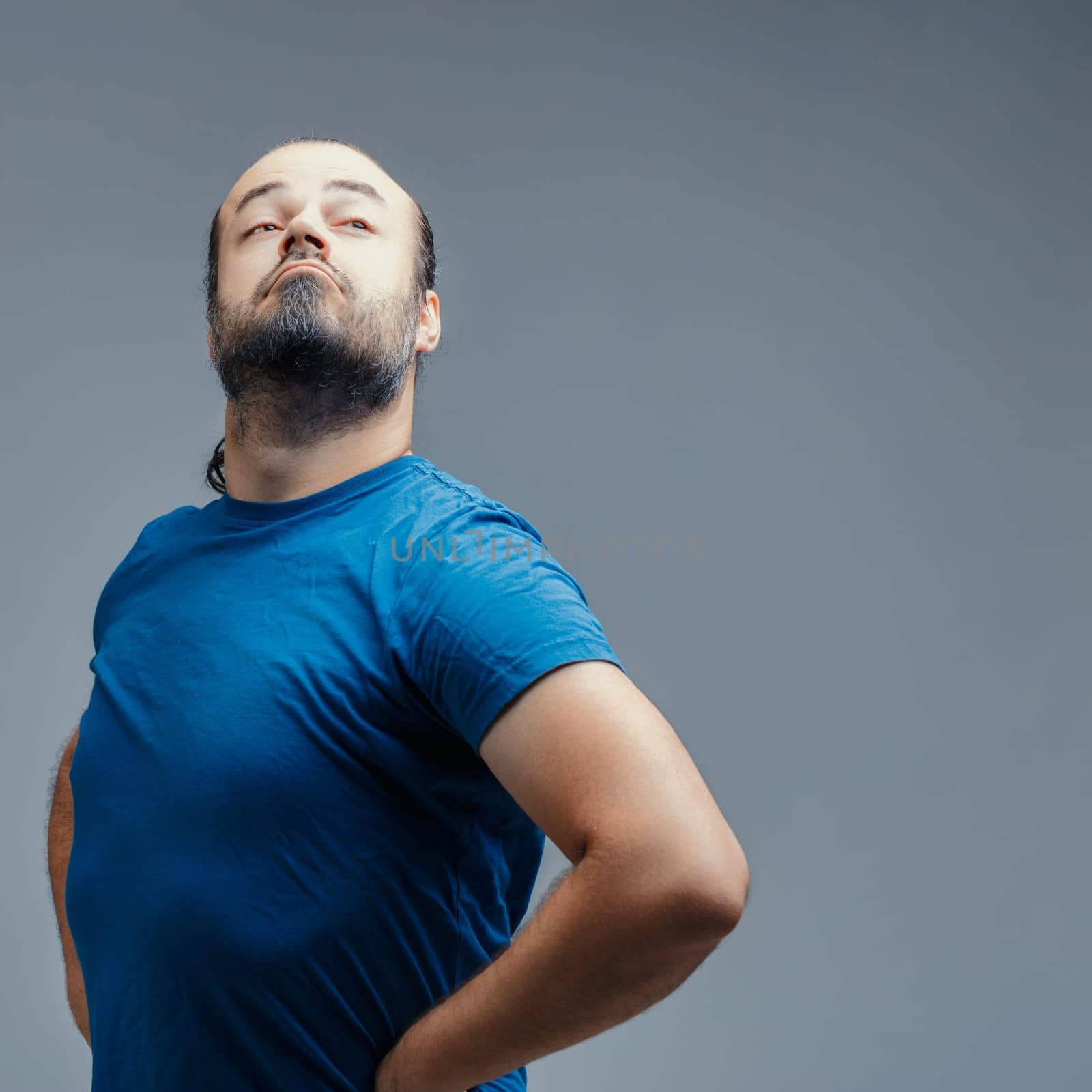Studio shot featuring a proud man puffing out his chest while looking down his nose, radiating an air of superiority and arrogance with a strong expression of self-importance