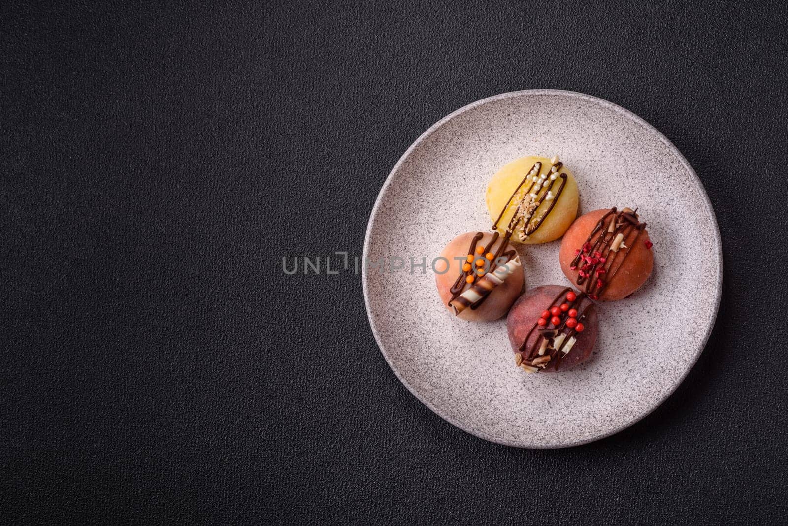 Delicious colorful asian mochi sweets with rice dough shell and fruit filling on dark concrete background
