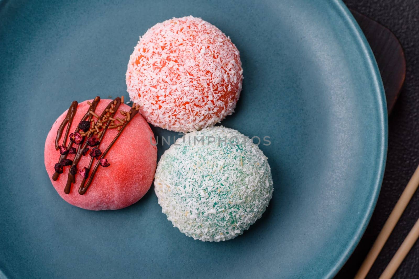 Delicious colorful asian mochi sweets with rice dough shell and fruit filling on dark concrete background