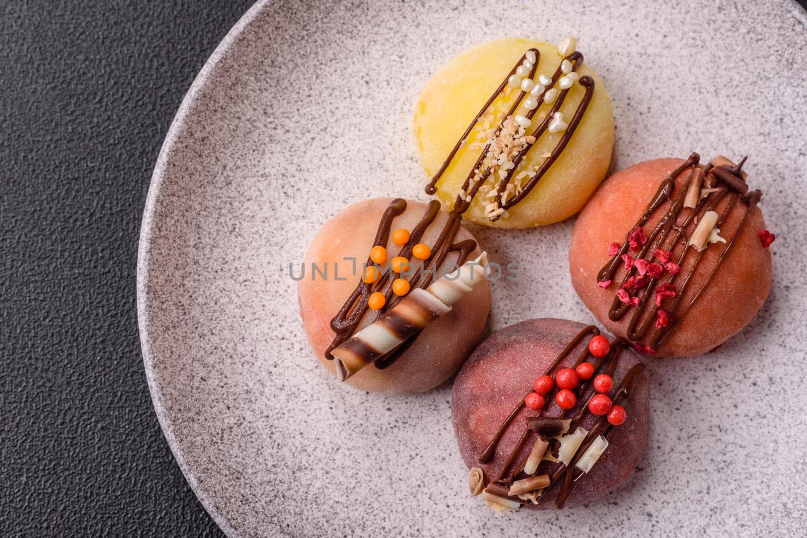 Delicious colorful asian mochi sweets with rice dough shell and fruit filling on dark concrete background