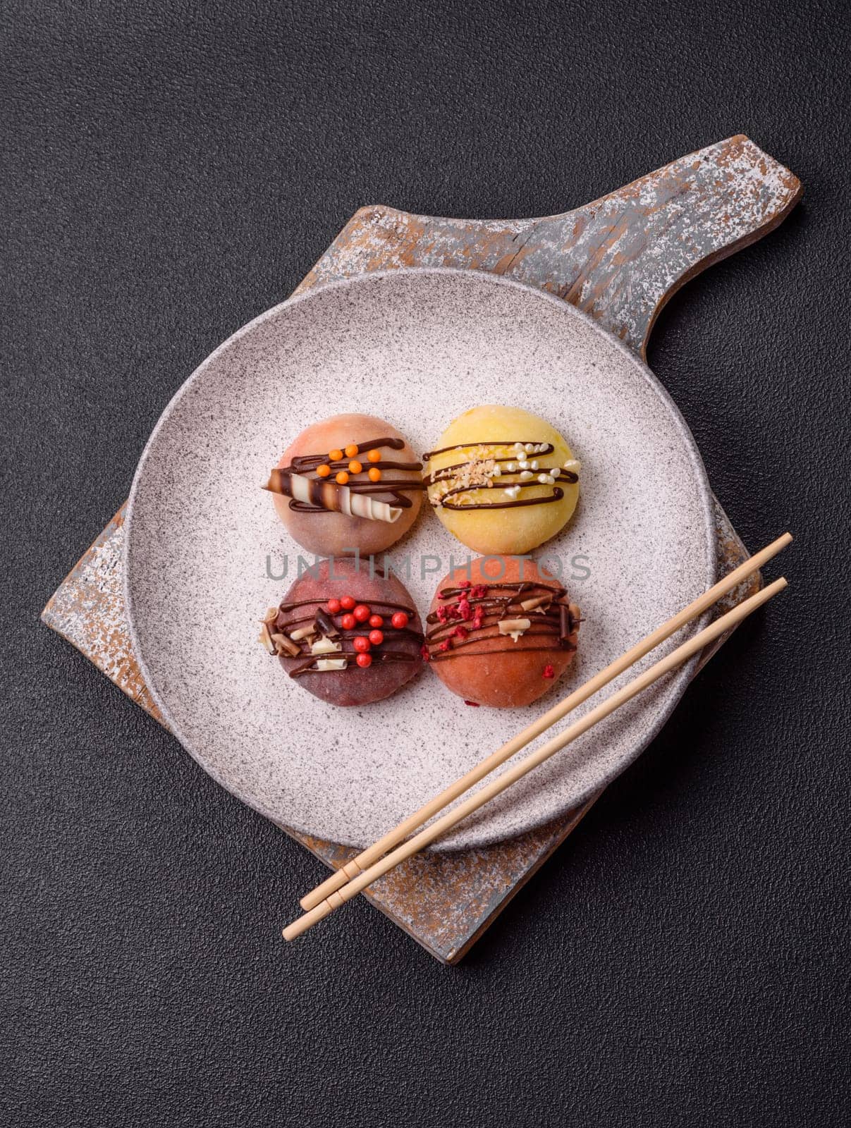 Delicious colorful asian mochi sweets with rice dough shell and fruit filling on dark concrete background