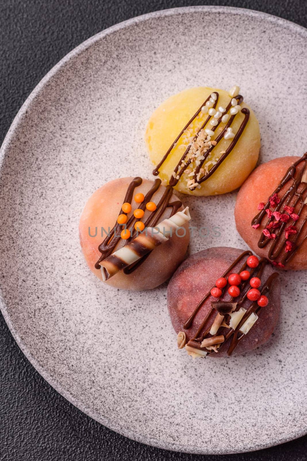 Delicious colorful asian mochi sweets with rice dough shell and fruit filling on dark concrete background