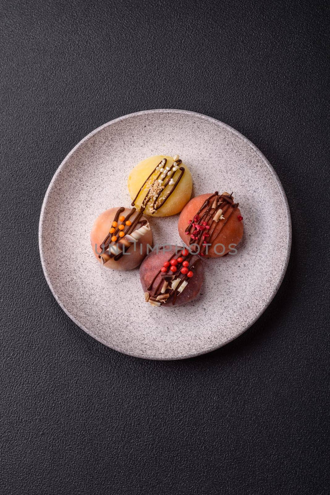 Delicious colorful asian mochi sweets with rice dough shell and fruit filling on dark concrete background