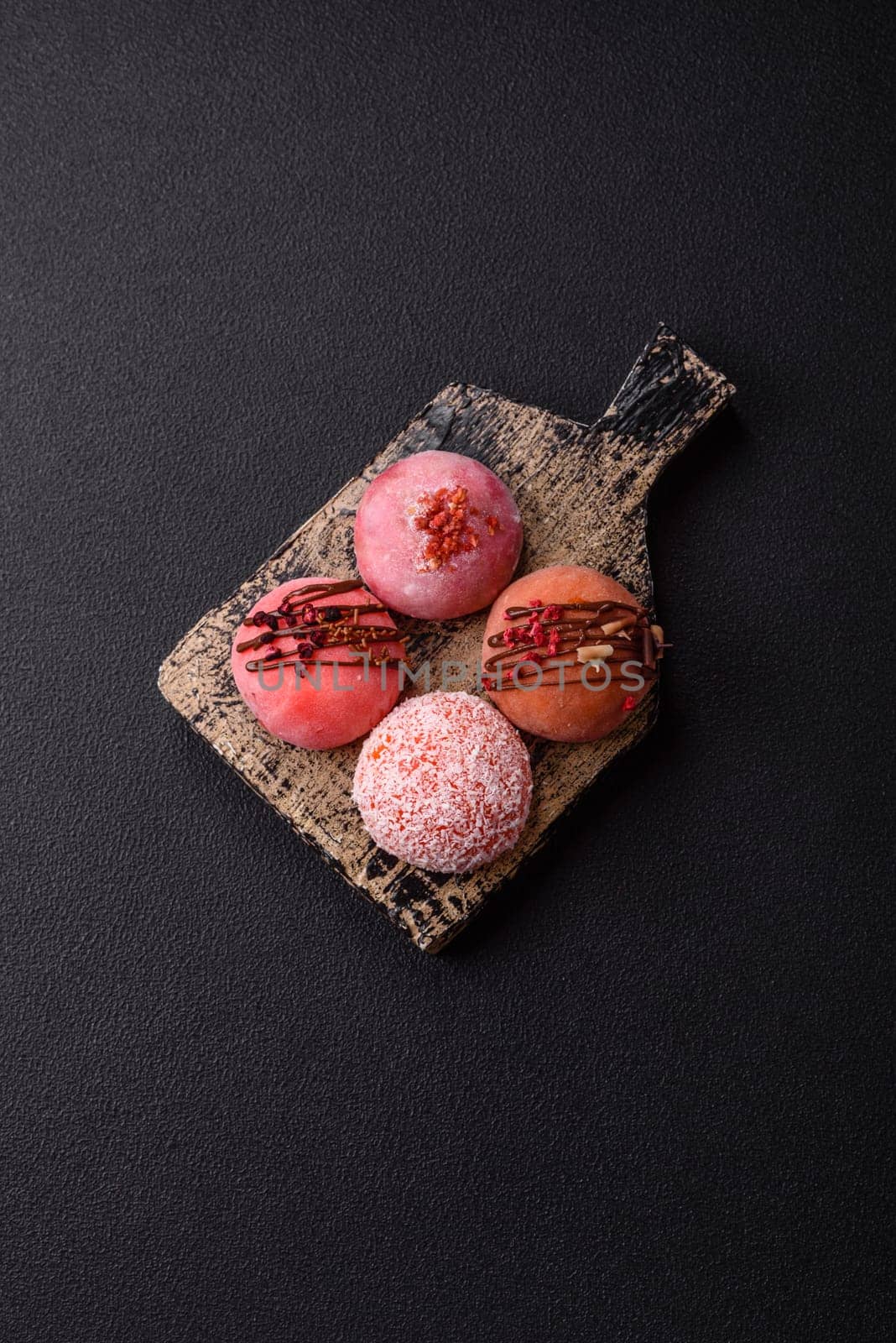 Delicious colorful asian mochi sweets with rice dough shell and fruit filling on dark concrete background