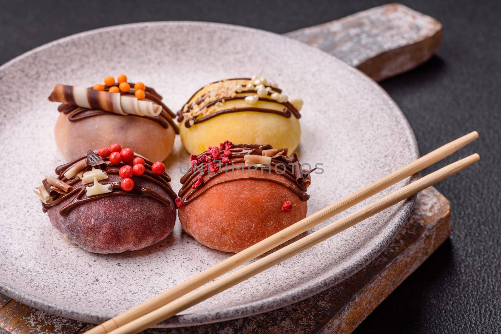 Delicious colorful asian mochi sweets with rice dough shell and fruit filling on dark concrete background