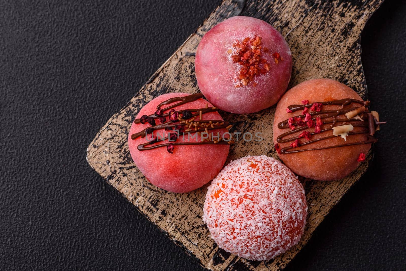 Delicious colorful asian mochi sweets with rice dough shell and fruit filling on dark concrete background