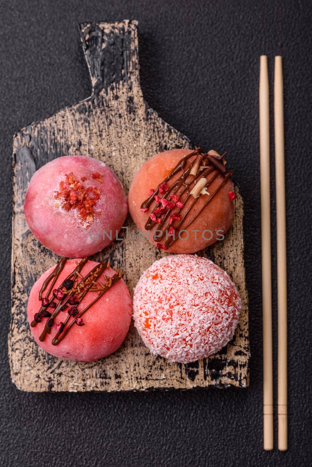 Delicious colorful asian mochi sweets with rice dough shell and fruit filling on dark concrete background