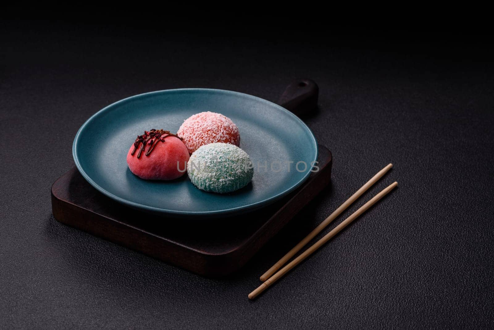 Delicious colorful asian mochi sweets with rice dough shell and fruit filling on dark concrete background