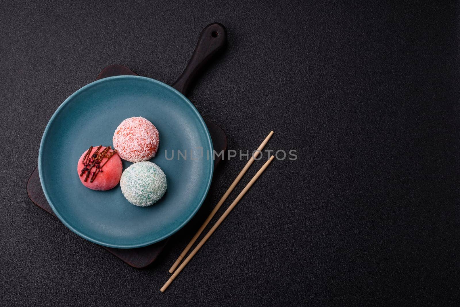 Delicious colorful asian mochi sweets with rice dough shell and fruit filling on dark concrete background