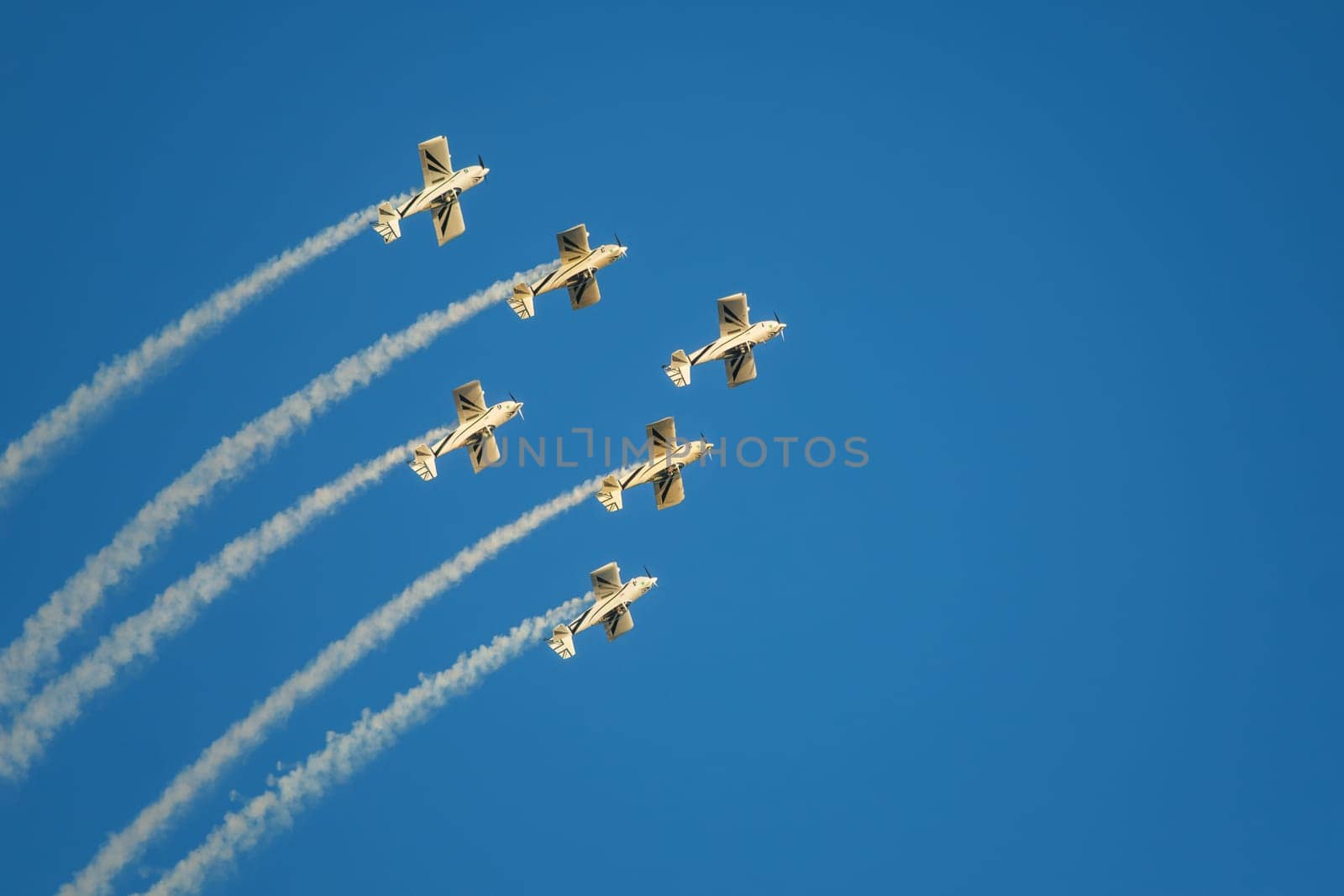 Stunt aerobatic planes in inverted flight performing stunts in blue sky with smoke trail. Concept of teamwork, collaboration, coordination, trust, precision, difficulty, challenge, speed, synergy