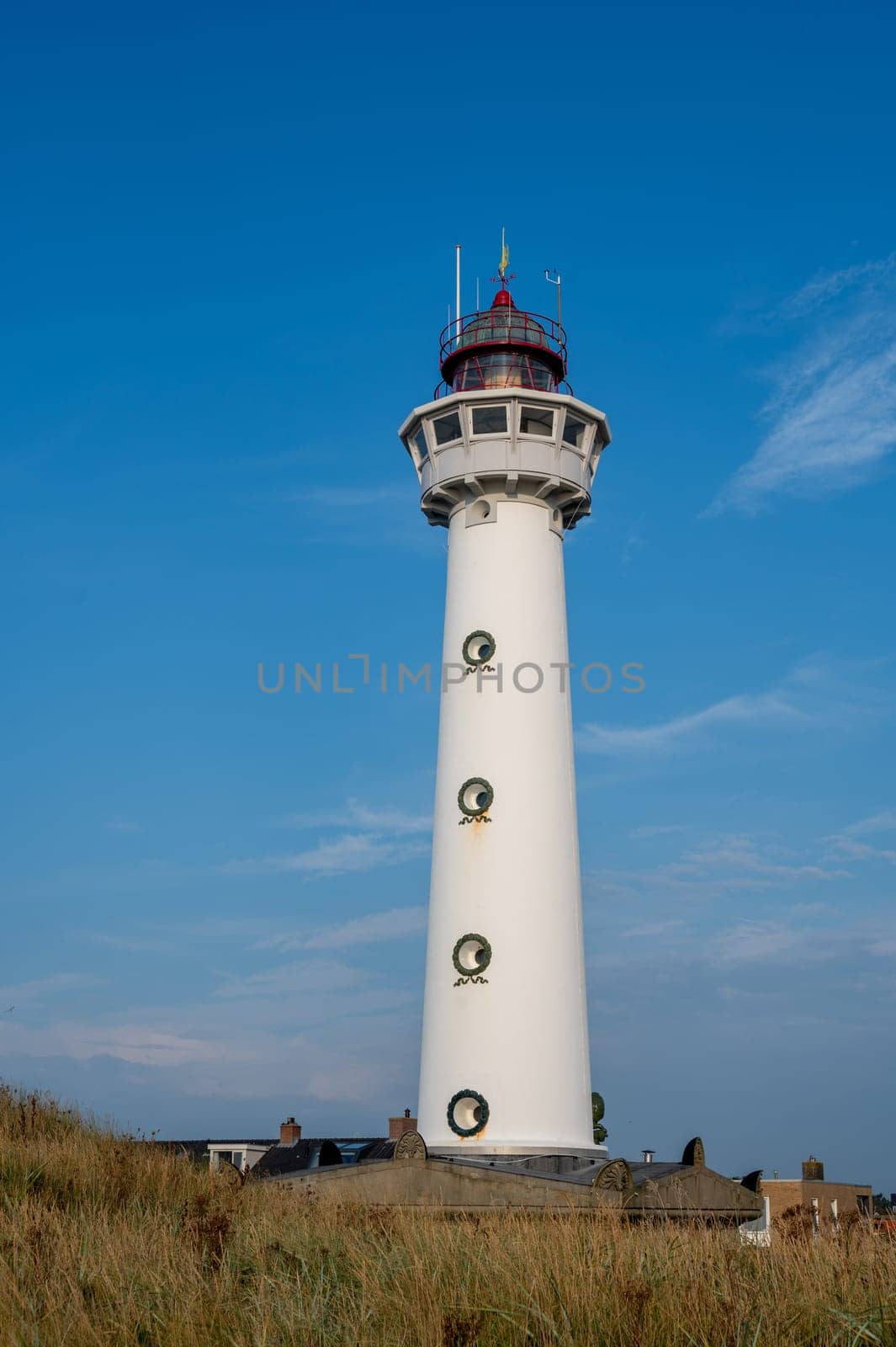 The approx. 28 m high white lighthouse J.C.J. van Speijk in Egmond aan Zee, North Holland, Netherlands, in the sand dunes with beach grass
